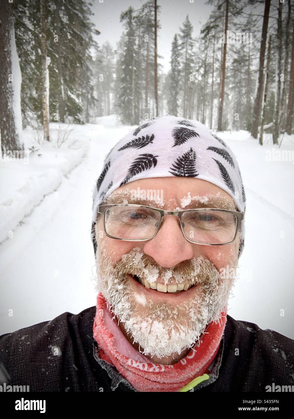 Ein lustiges Selfie eines Mannes mittleren Alters mit Eisbart, der in der extremen Kälte des tiefgefrorenen Winters im nördlichen Polarkreis Finnlands gelaufen ist Stockfoto