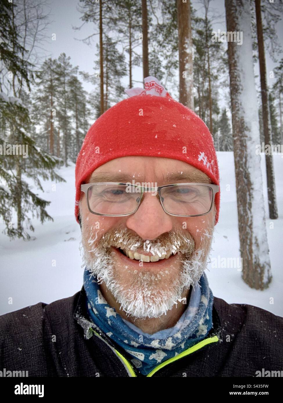 Ein lustiges Selfie eines Mannes mittleren Alters mit Eisbart, der in der extremen Kälte des tiefgefrorenen Winters im nördlichen Polarkreis Finnlands gelaufen ist Stockfoto