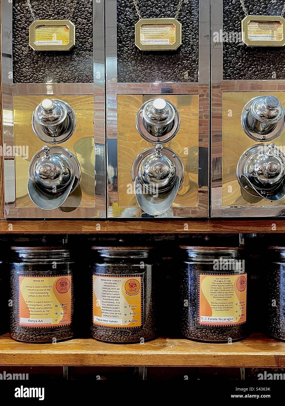 Kaffeebohnen. Wand des Cafés mit 3 etikettierten Kaffeemühlen für Kaffeebohnen. - Smartphone-aufgenommenes Stockfoto