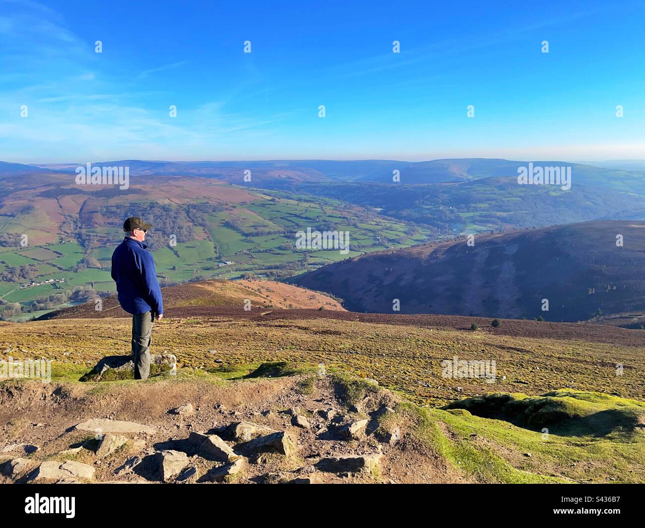 Ein Mann, der nordöstlich vom Gipfel des Sugaloaf Berges blickt, Abergavenny, Brecon Beacons, Wales, April. Stockfoto