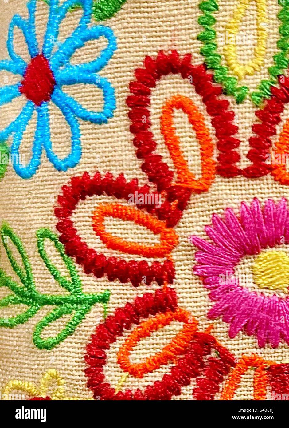 Farbenfrohes, strukturiertes Hippie-Boho-Material mit farbenfrohen, gestickten Gänseblümchen. Stockfoto