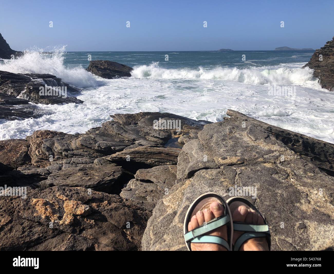 Die Meereswellen von den Felsen aus beobachten. - Smartphone-aufgenommenes Stockfoto
