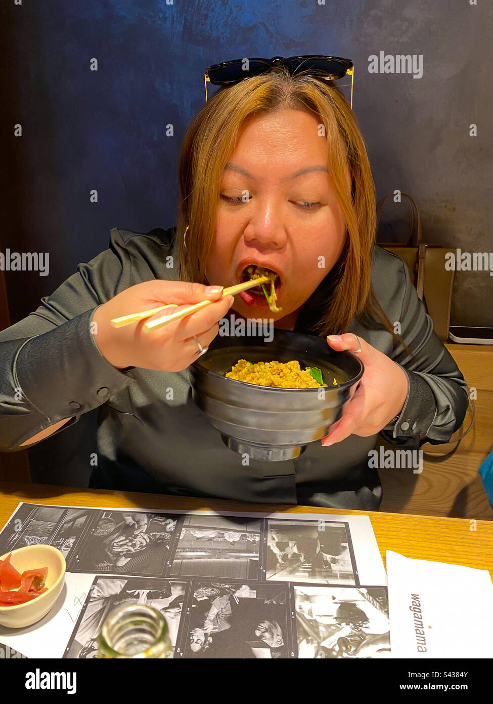 Eine asiatische Dame, die eine Schüssel Reis mit Stäbchen isst. Stockfoto