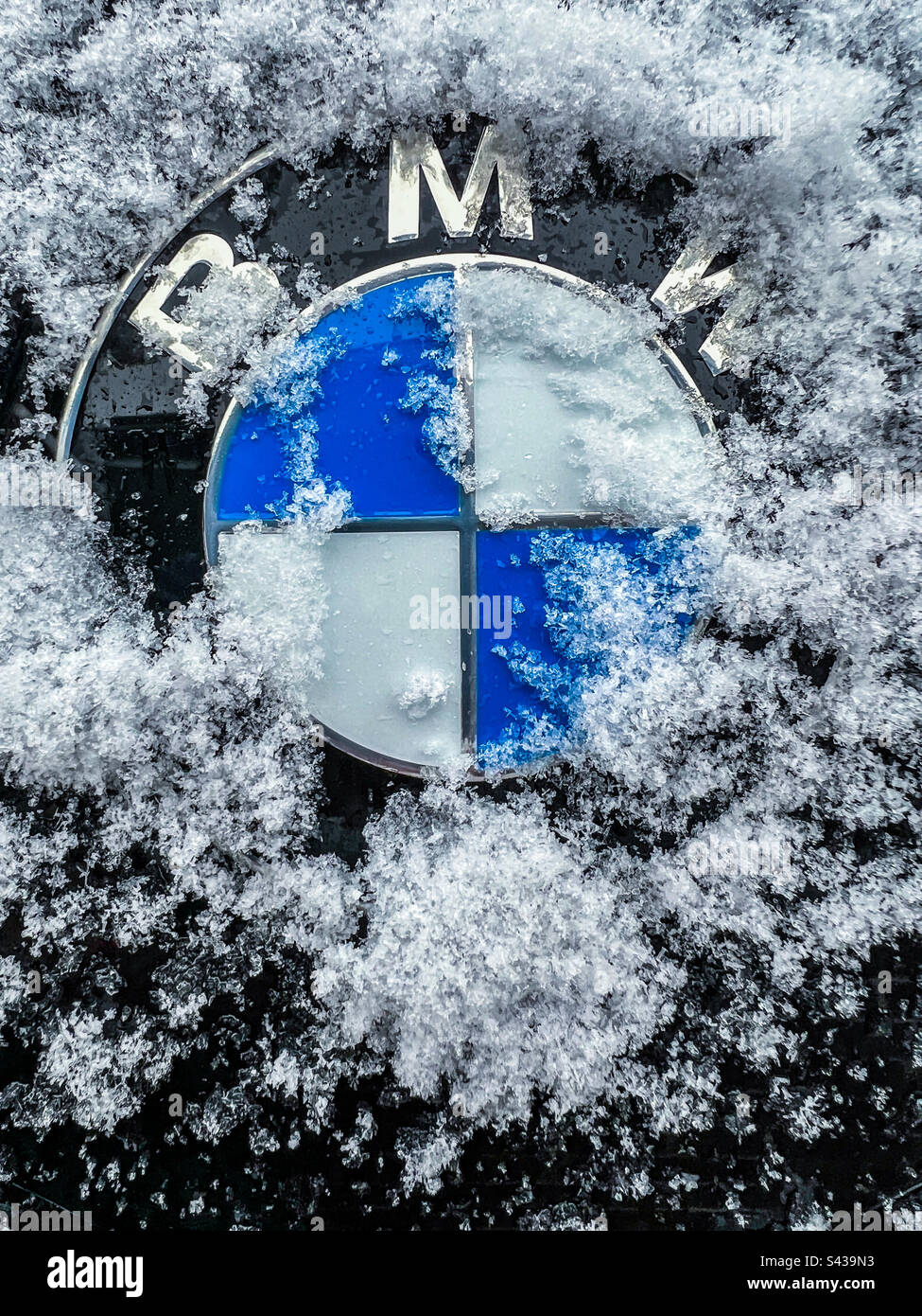 BMW-Logo teilweise mit Schnee bedeckt - Smartphone-aufgenommenes Stockfoto