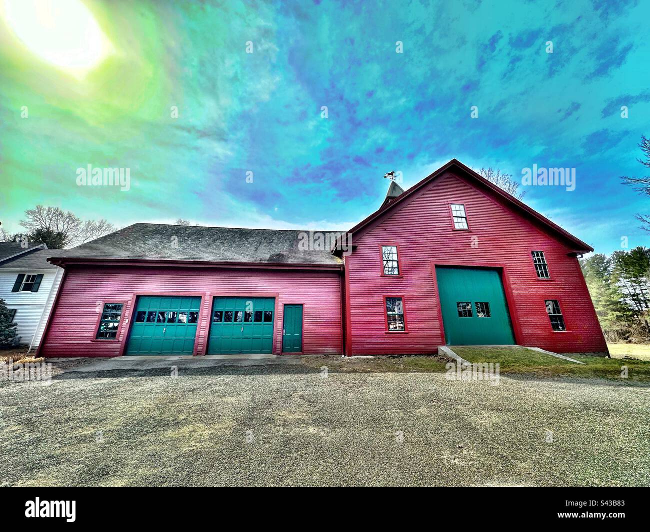 Große rote Scheune in Concord, Massachusetts, USA, mit grünen Türen. Der Filter verwandelt den Himmel in Science-Fiction-ähnliche Elemente. - Smartphone-aufgenommenes Stockfoto