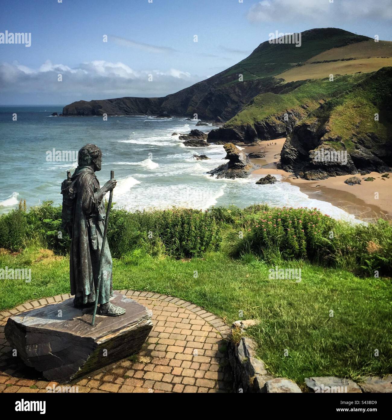 Die Statue von Saint Crannog überblickt den beliebten Llangrannog-Strand an einem dramatischen Abschnitt des beliebten Ceredigion Coast Path in West Wales Stockfoto