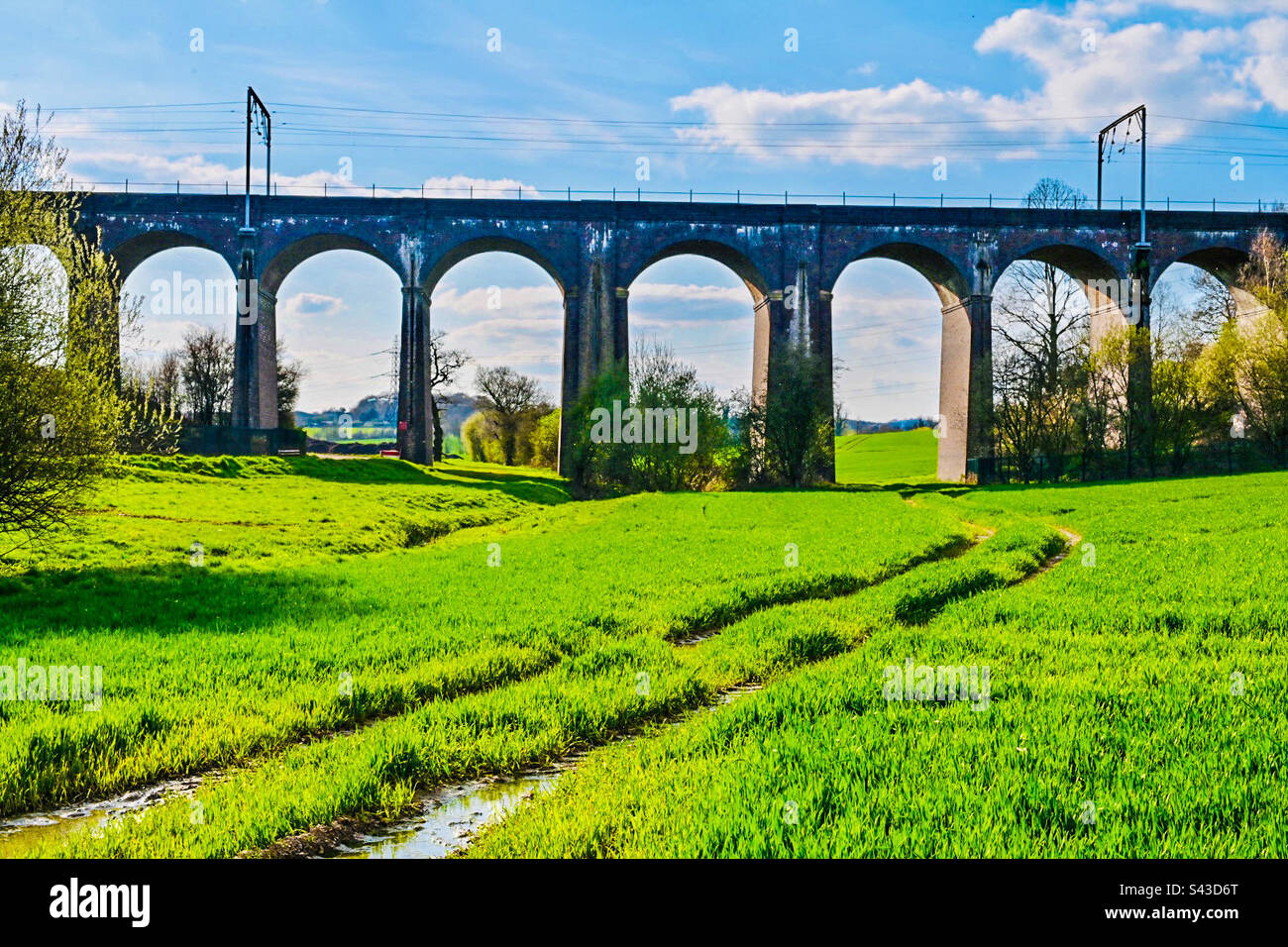Eine Eisenbahnbrücke über sehr grünes Gras in einer ländlichen Gegend von London Stockfoto