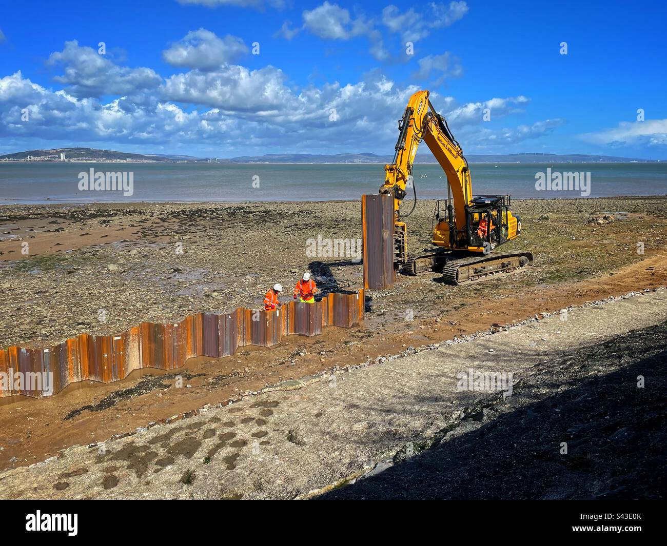 Arbeiter, die die Meeresabwehr auf der Mumbles Promenade verstärken, Swansea, Wales, April 2023. Stockfoto