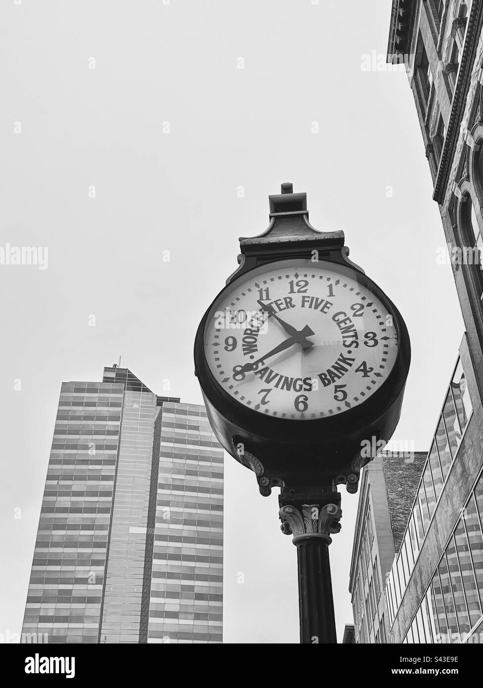 Altmodische Uhr im Stadtzentrum von Worcester, Massachusetts, USA. Moderner Wolkenkratzer in der Ferne. Schwarzweißfilter. Stockfoto