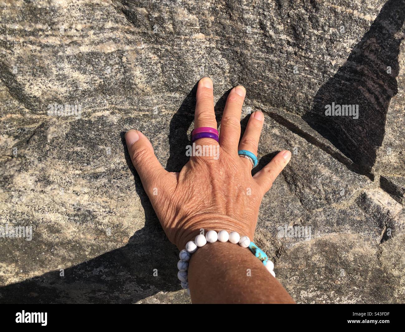 Die Hand einer Frau auf einem Stein. - Smartphone-aufgenommenes Stockfoto