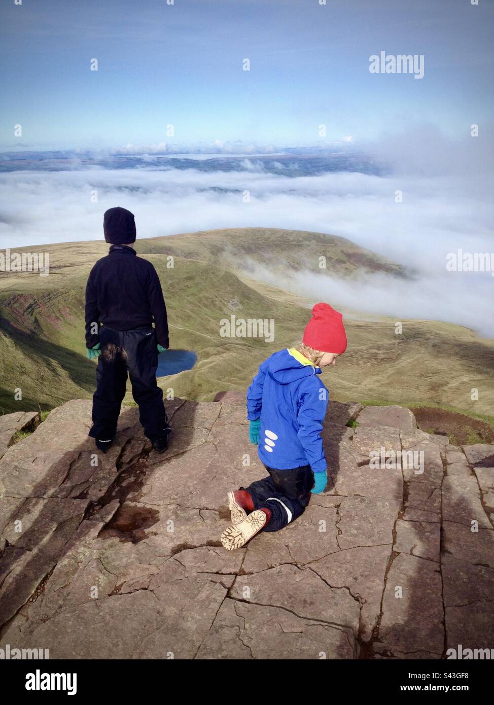 Im Brecon Beacons Bannau Brycheiniog in Wales spielen zwei Kinder auf dem Pen y Fan-Berg über den Wolken. Dies ist der höchste Gipfel im südlichen Teil des Vereinigten Königreichs. Stockfoto