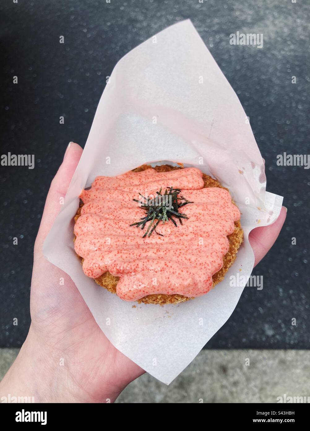 Hand mit einer Monjya Croquette, Tsukiji Fish Market, Tokio, Japan - Smartphone-aufgenommenes Stockfoto