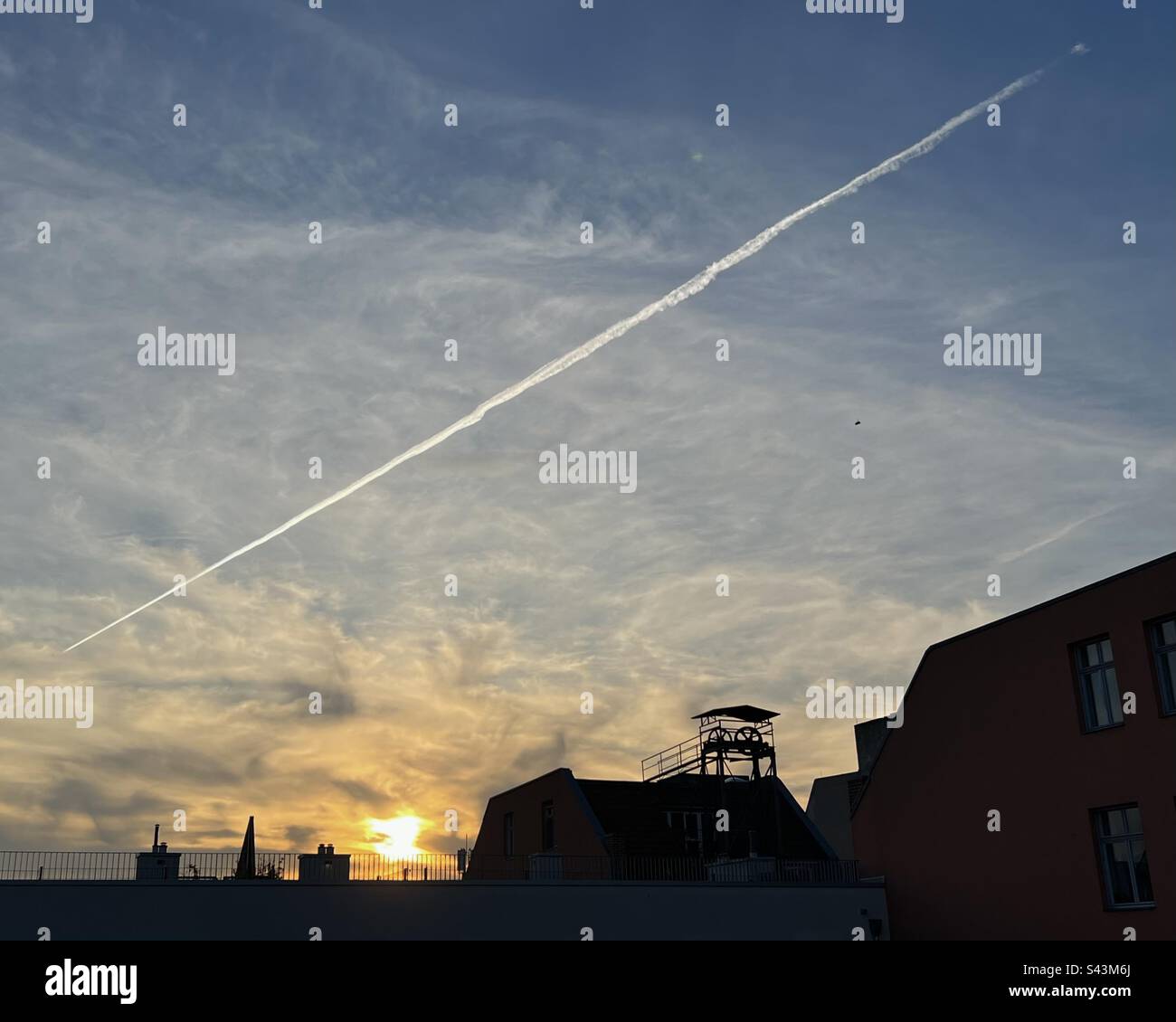 Sonnenuntergang und Flugzeugkondensationsspur über dem Dach des Wohnungsgebäudes, Mitte, Berlin, Deutschland Stockfoto