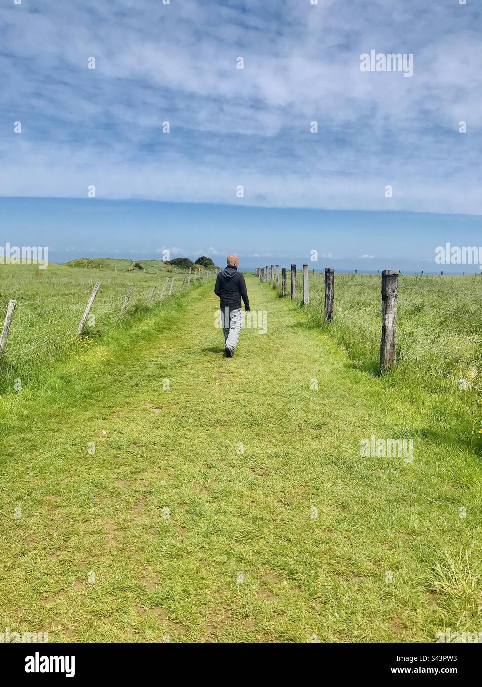 Ein Mann, der in Richtung Meer geht, im ländlichen Neuseeland Stockfoto