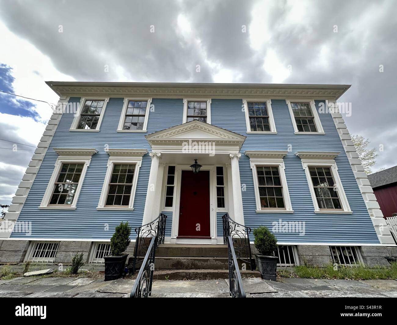 Klassisches blaues Haus in East Haddam, Connecticut, USA, mit Wolken im Hintergrund. Steingrundlagen. Mit Weitwinkelobjektiv aufgenommen. Stockfoto