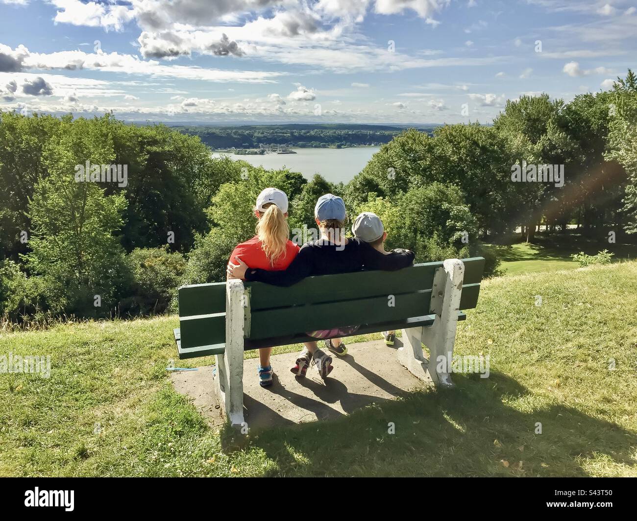 Eine Mutter und zwei ihrer Kinder machen eine Pause auf einer Parkbank in den Plains of Abraham mit Blick auf die St. Lawrence-Fluss. Stockfoto
