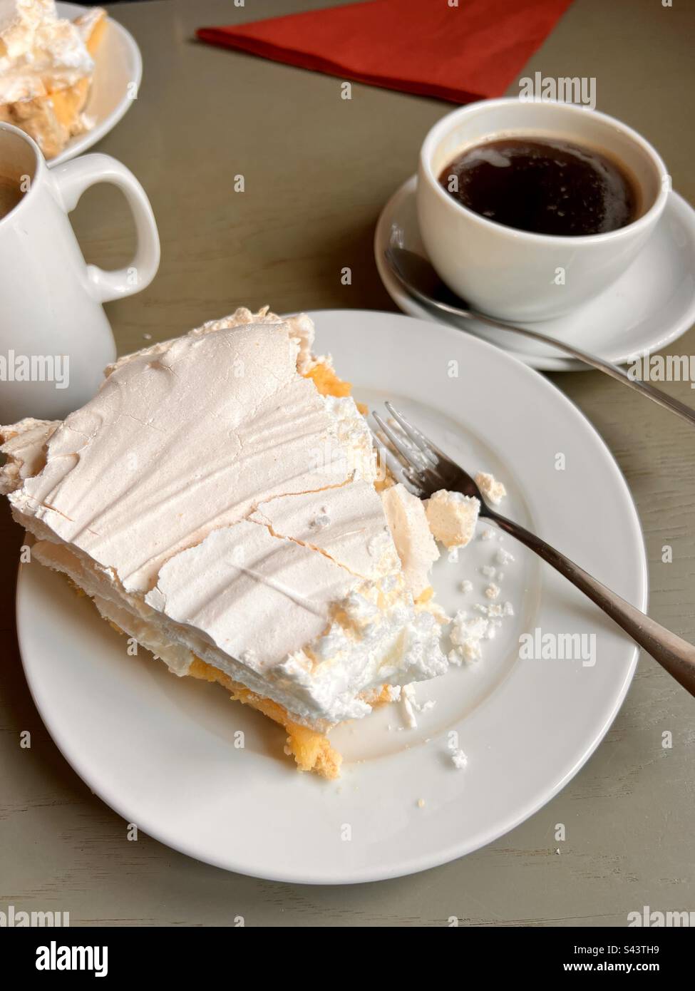 Große Portion Zitronen-Baiser-Kuchen mit Kaffee Stockfoto