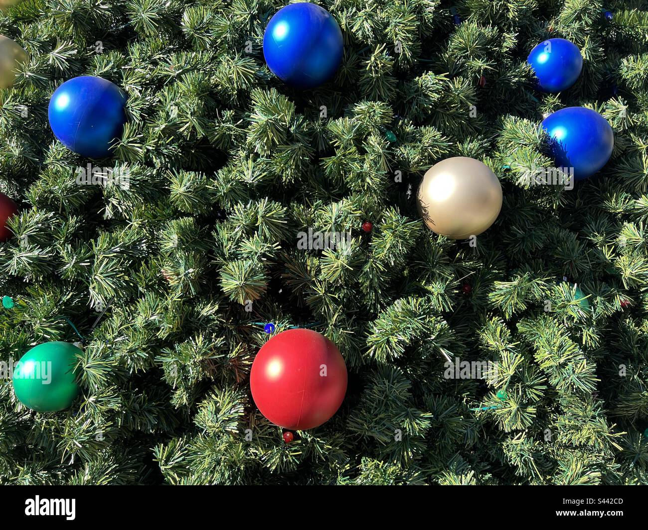 Details großer roter, blauer, weißer und grüner Ornamente auf einem riesigen künstlichen Weihnachtsbaum im Freien in Südkalifornien Stockfoto