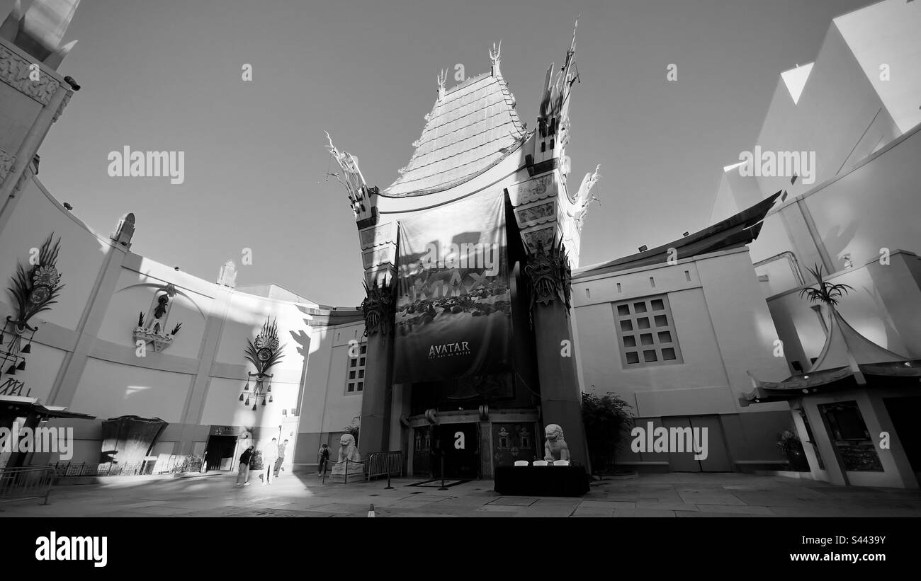 LOS ANGELES, CA, 2022. DEZEMBER: Historische Fassade des TCL Chinese Theater, der Filmvorführung des Avatar-Films in Hollywood. Eine Gruppe von Besuchern wird von der frühen Morgensonne erleuchtet. Schwarz auf Weiß - Smartphone-aufgenommenes Stockfoto