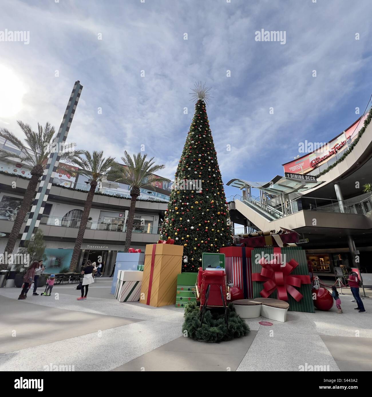 SANTA MONICA, CA, 2022. DEZEMBER: Weihnachtsdekorationen mit riesigem Weihnachtsbaum, und Leute, die in Geschäften im Open-Air-Einkaufszentrum einkaufen Stockfoto