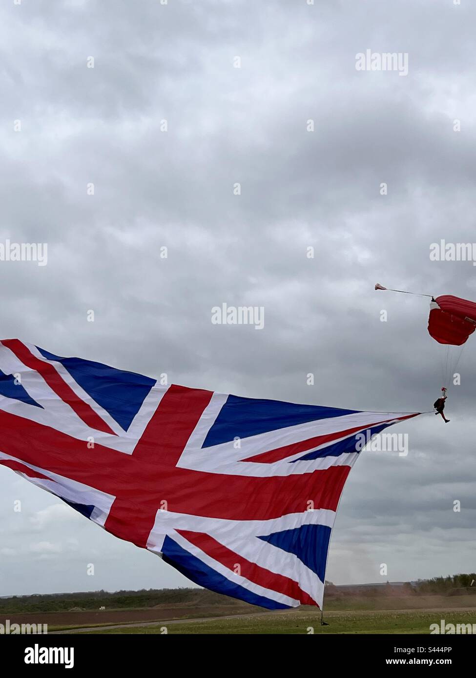 Red Devils Fallschirmteam mit einem riesigen Union Jack, der am Himmel fliegt Stockfoto