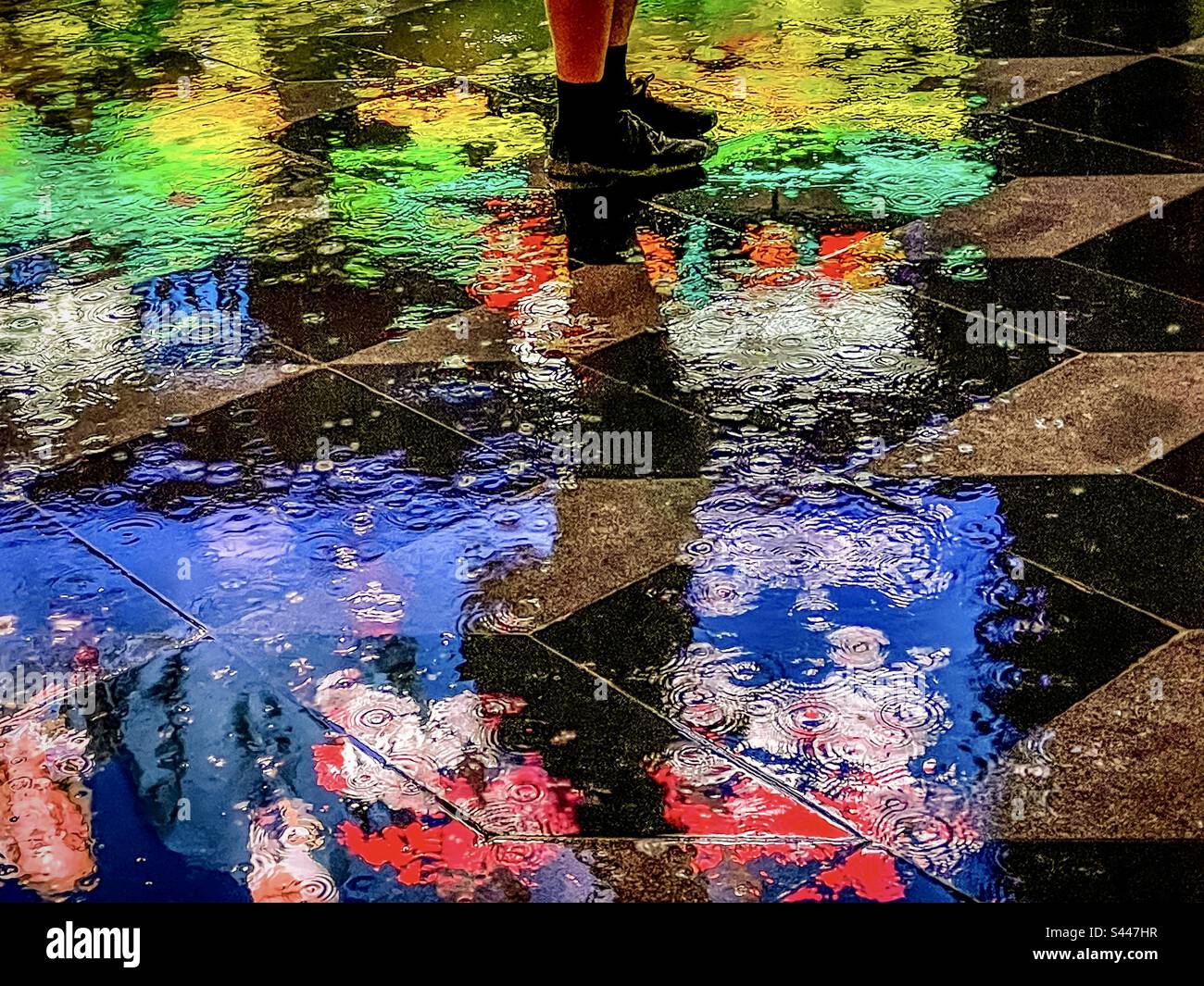 Tiefer Abschnitt der Beine und Füße des Menschen auf nassen, reflektierenden Pflasterfliesen mit farbenfrohen, lebendigen Reflexionen von Neonlichtern in einer regnerischen Nacht. Art. Saure Farbpalette. Märchenhafter Stil. Van Gogh-Stil. Stockfoto