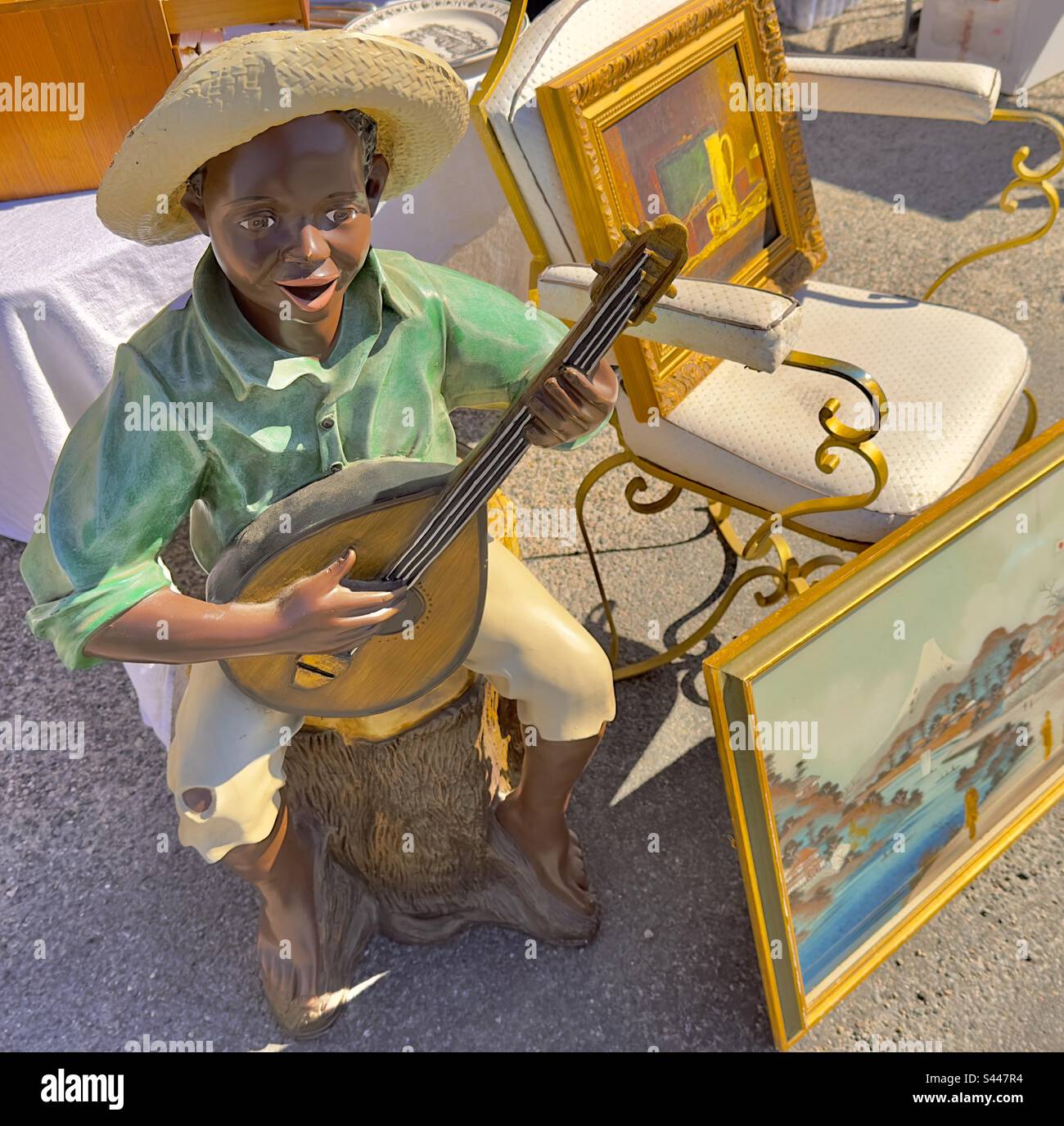 Eine kleine Statue eines schwarzen Jungen, der auf einem französischen Flohmarkt ein Saiteninstrument spielt Stockfoto