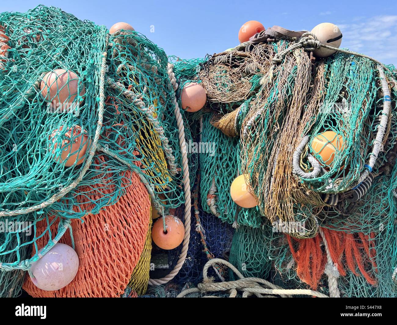 Ein Bündel von Fischernetzen, Leinen und Bojen, die sich im Sommer an der Seite des Hafens von Lyme Regis in Dorset, England, stapeln Stockfoto