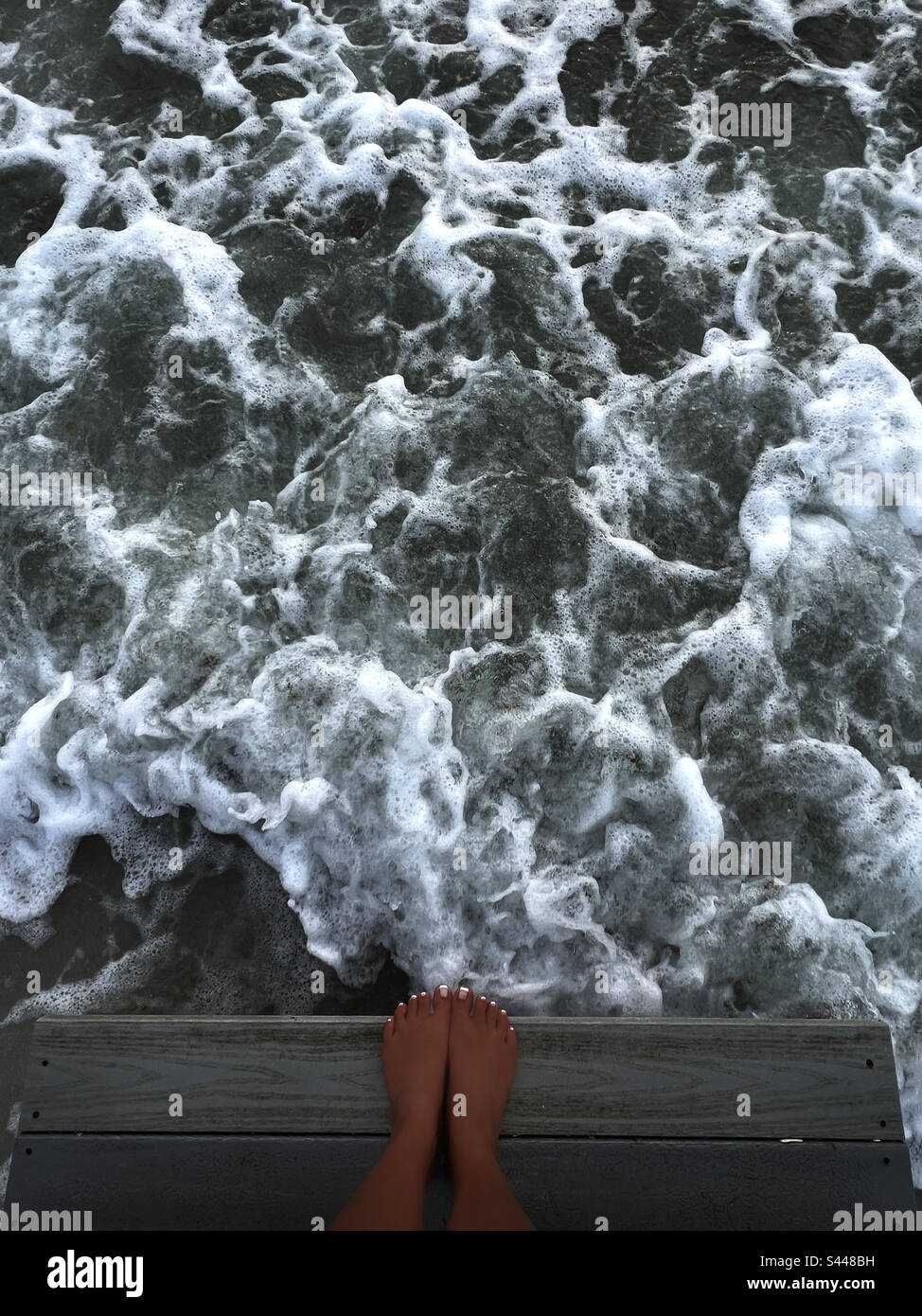Füße auf Stufen am Meer - Smartphone-aufgenommenes Stockfoto