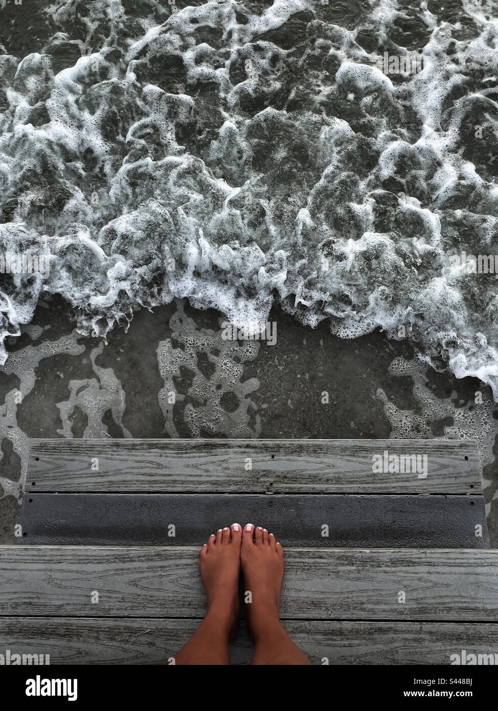 Füße auf Stufen ins Meer - Smartphone-aufgenommenes Stockfoto