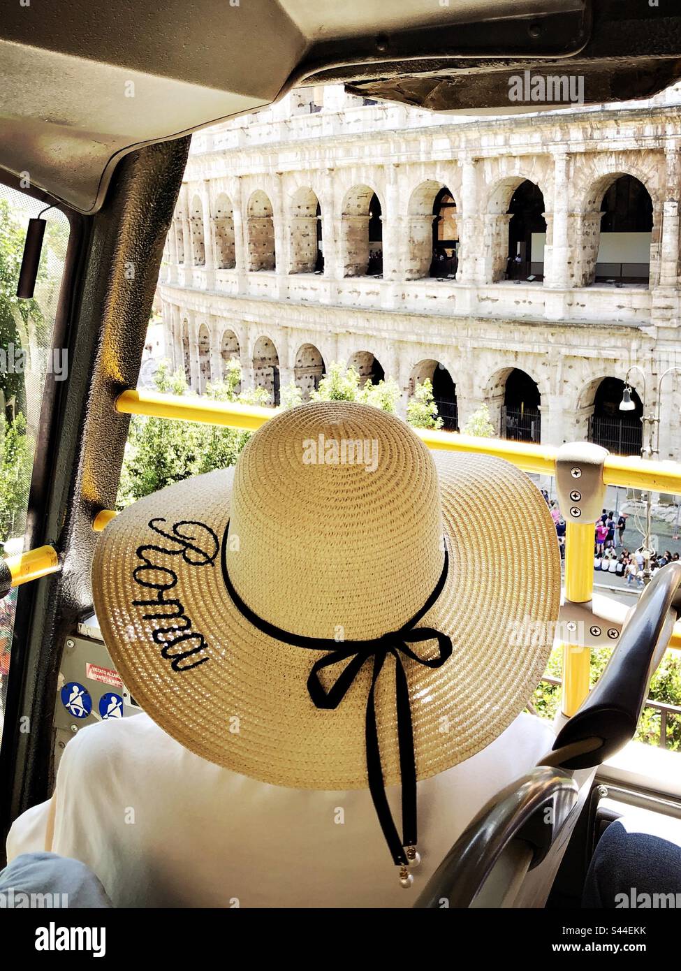 Eine Frau mit Strohhut, die das Kolosseum von einem Tourbus aus in Rom, Italien, ansieht - Smartphone-aufgenommenes Stockfoto