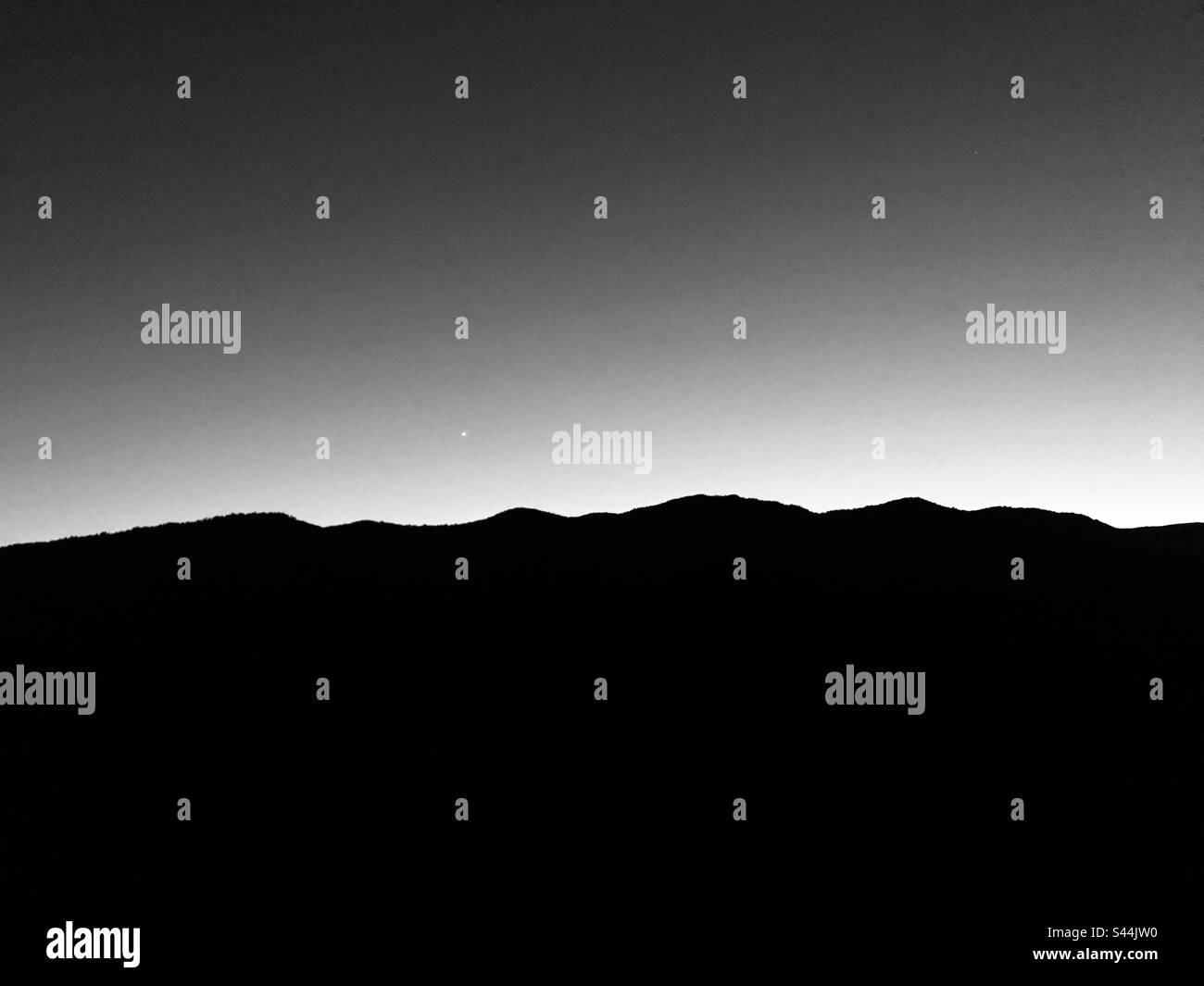 Schwarz-Weiß-Aufnahme einer Hügelsilhouette über dem Himmel Stockfoto