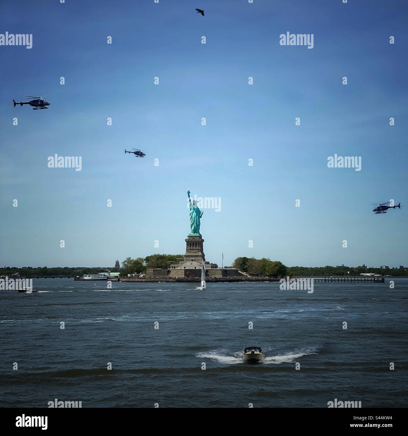 Die Freiheitsstatue im Hafen von New York, voll mit Hubschraubern, Booten und einem Vogel, der über Ihnen fliegt Stockfoto