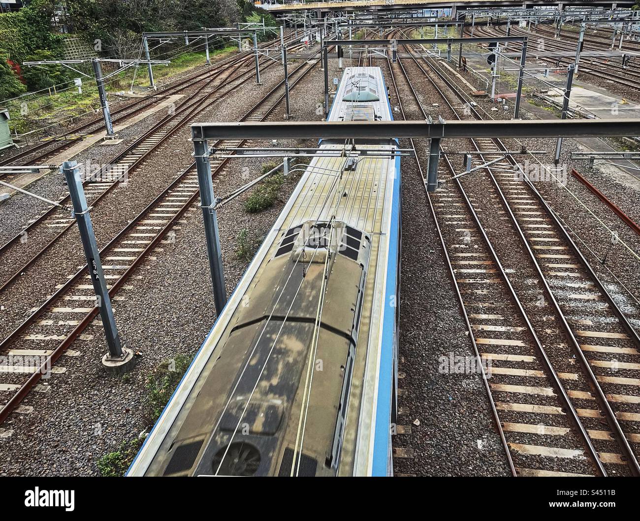 Blick von oben auf den Zug, der sich auf der Eisenbahnstrecke bewegt. Stockfoto