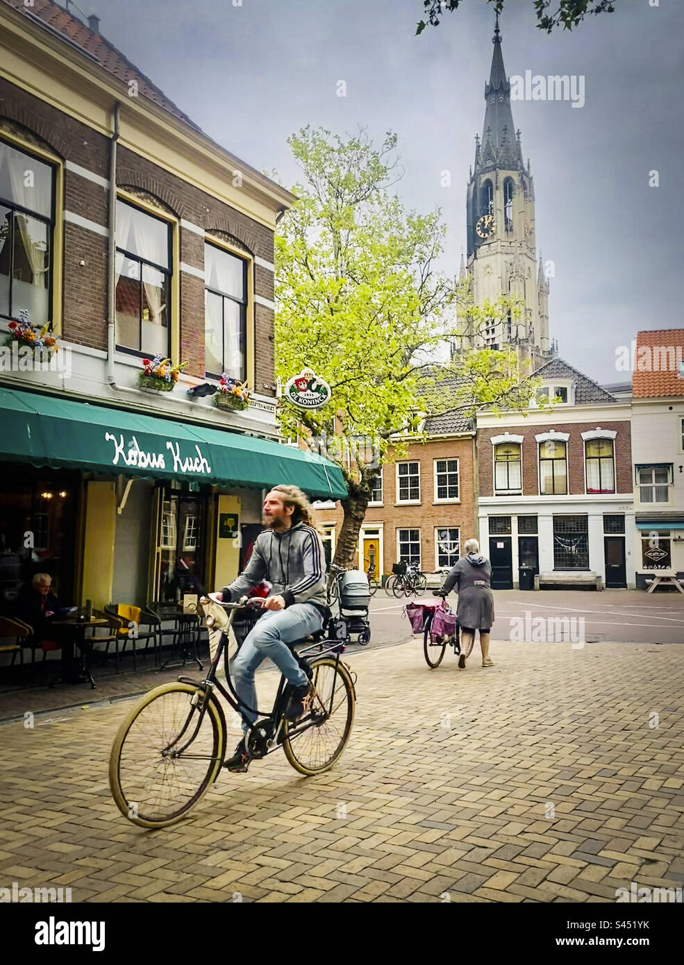 Ein Mann mit langem Haarzyklus durch Delft in den Niederlanden - Smartphone-aufgenommenes Stockfoto
