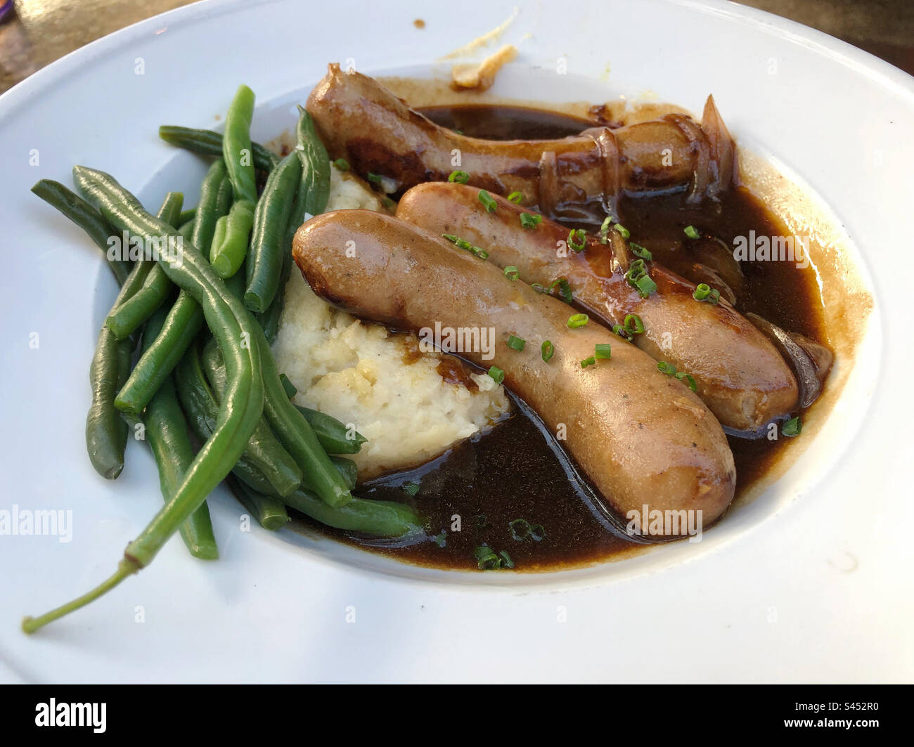 Die britischen Knaller und Püree mit grünen Bohnen. - Smartphone-aufgenommenes Stockfoto