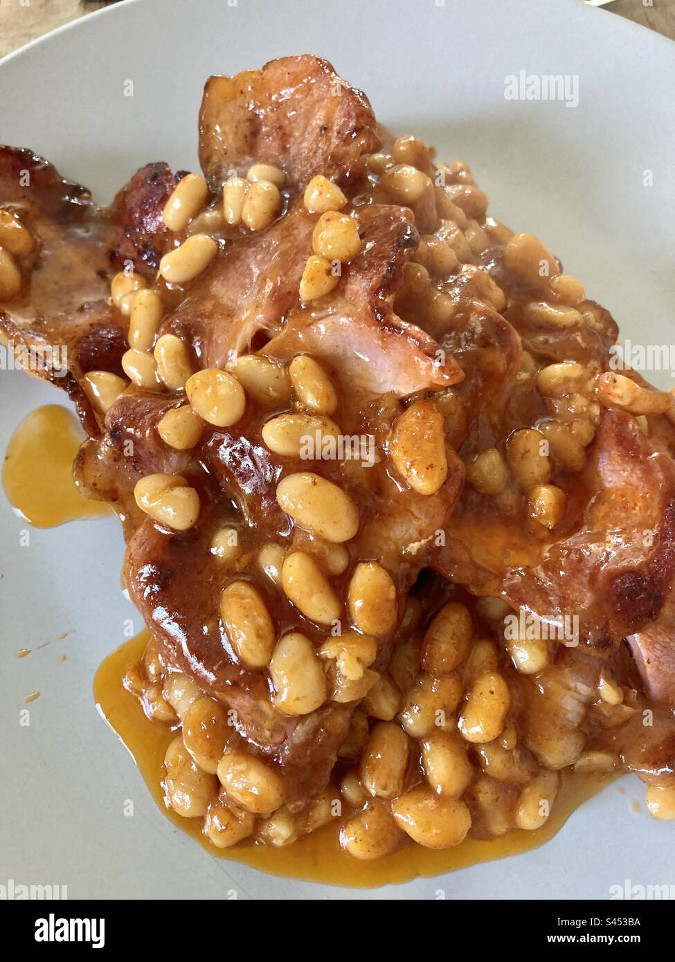 Frühstück mit Speck und Bohnen in Großbritannien - Smartphone-aufgenommenes Stockfoto