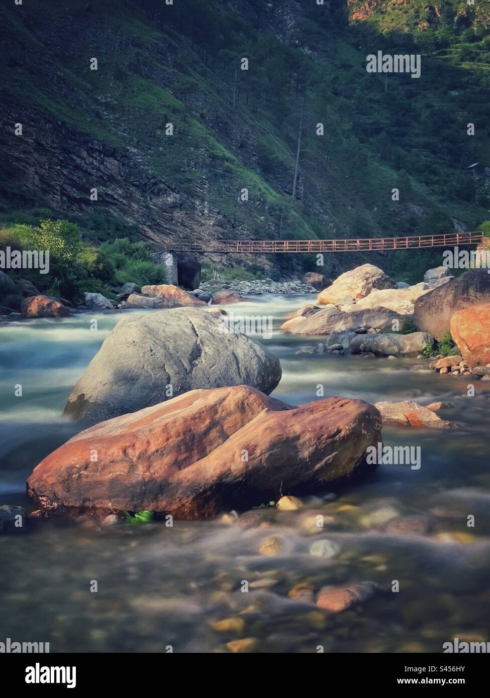 Felsen im Fluss mit Brücke Stockfoto