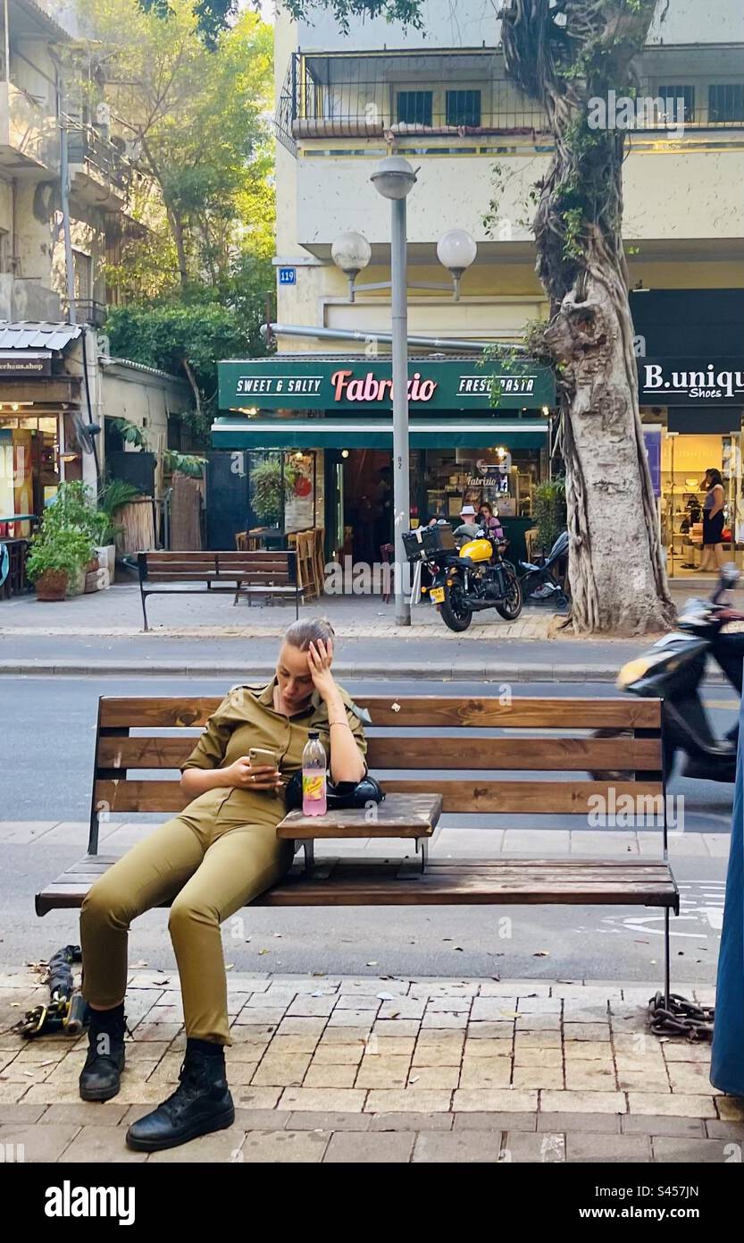 Eine israelische Soldatin ruht auf einer Bank in Tel-Aviv, Israel. Stockfoto