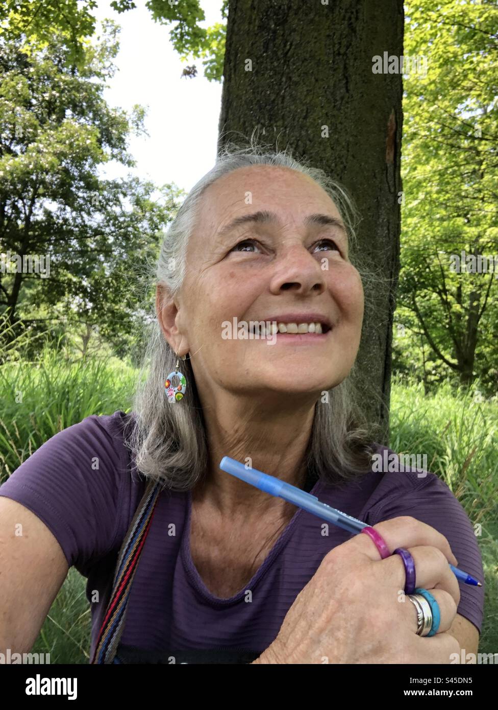Eine Frau im Wald, die in den Himmel blickt und denkt. Stockfoto