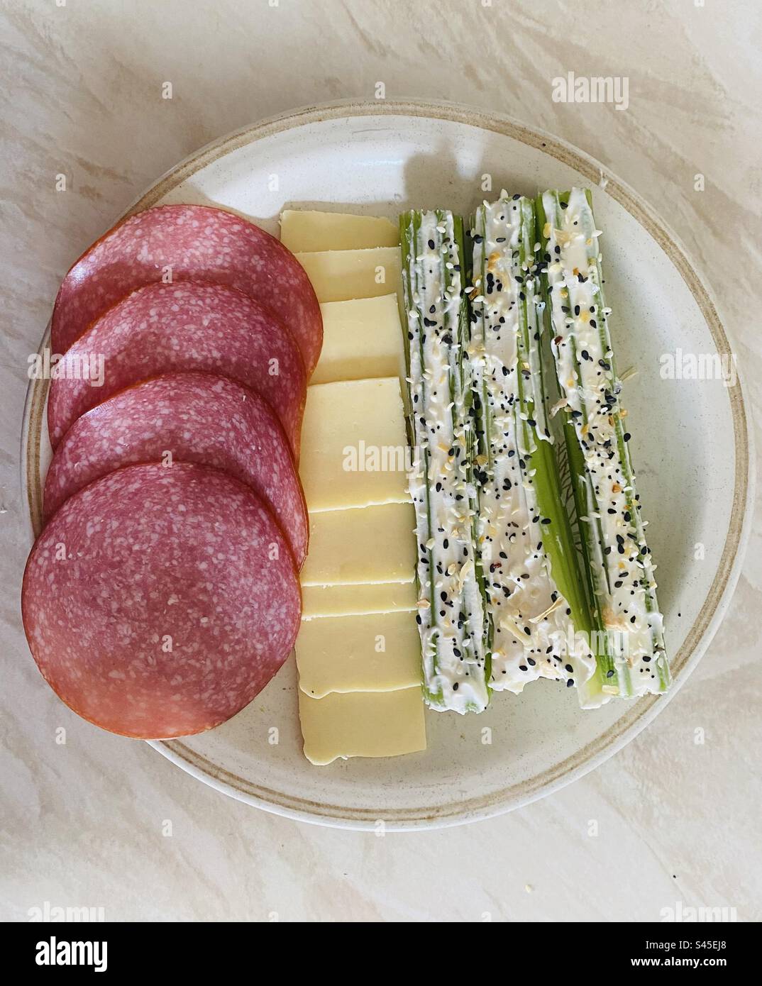 Keto Friendly Teller - Deutsche Salami, Applewood Käse und Sellerie gefüllt mit Weichkäse und mit nichts als Bagel Gewürzen bestreut. Stockfoto