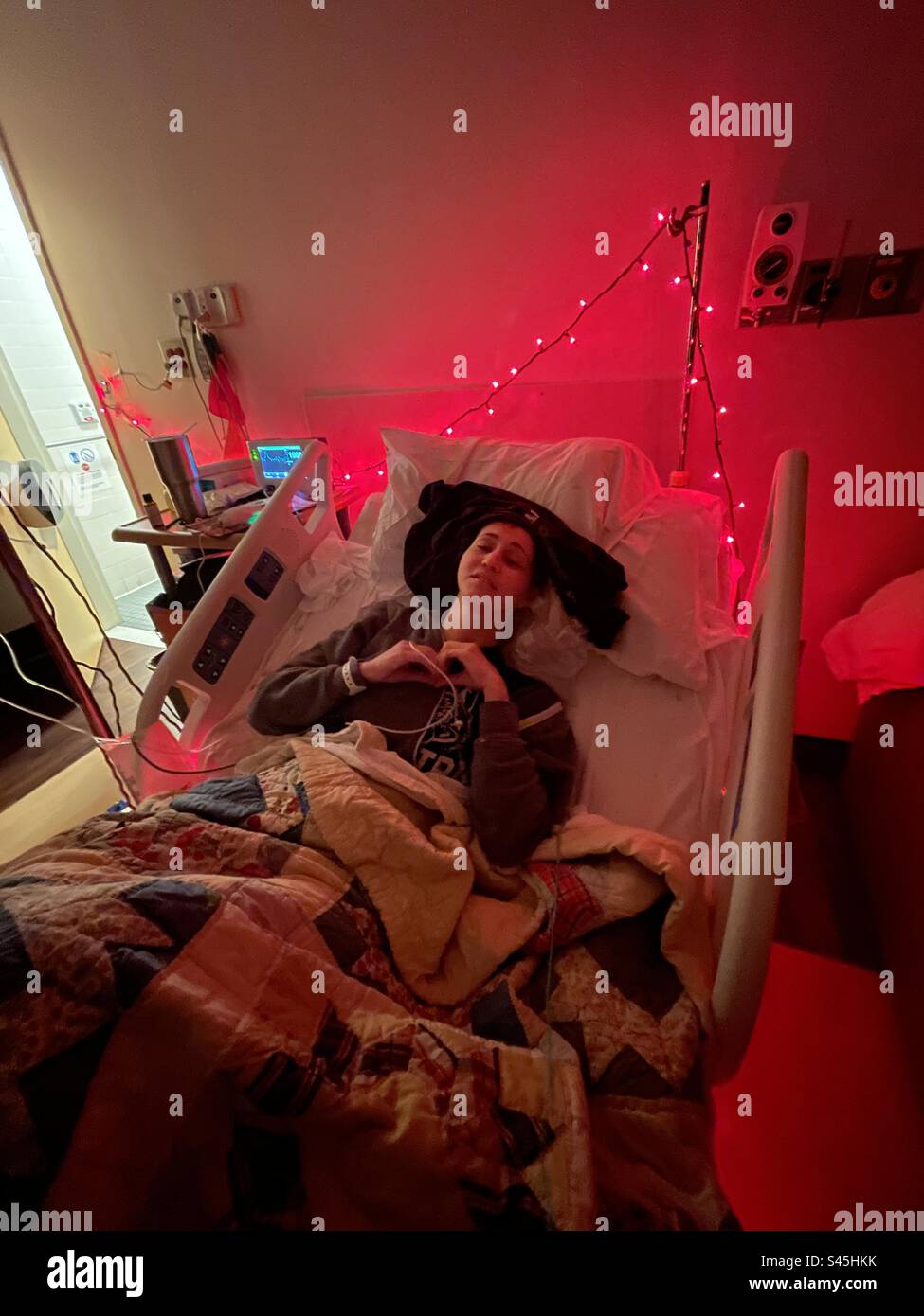 Die Frau liegt nach Operationen an der Wirbelsäule im Krankenhausbett mit roten Lichtern Stockfoto