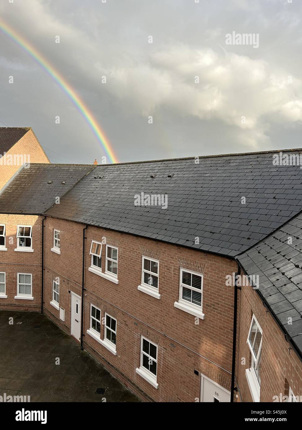 Regenbogen über Vorstadtdächern in Aylesbury, England. - Smartphone-aufgenommenes Stockfoto