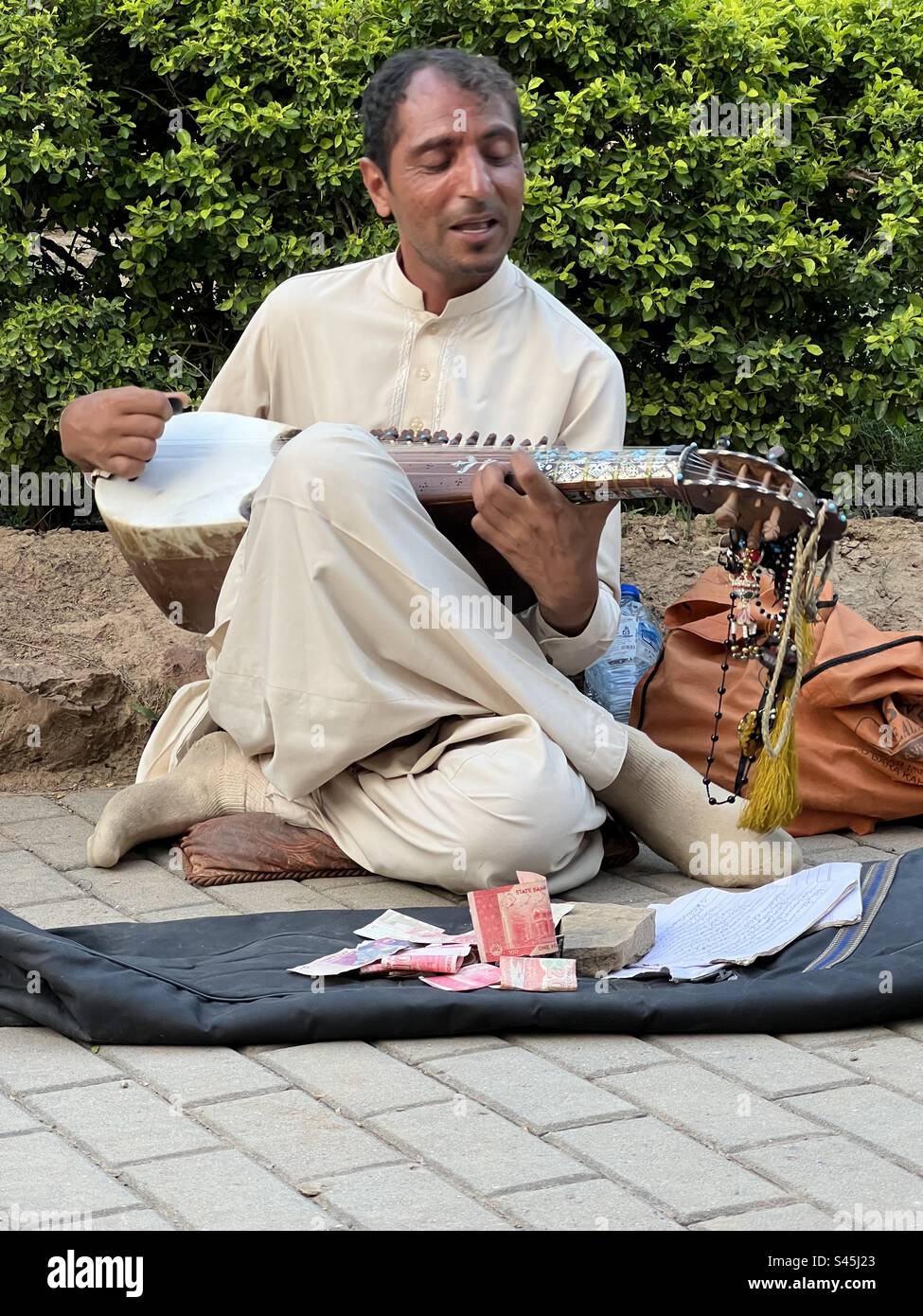 Straßenmusiker, der in Islamabad, Pakistan, mit einem gummierten Saiteninstrument spielt. Stockfoto