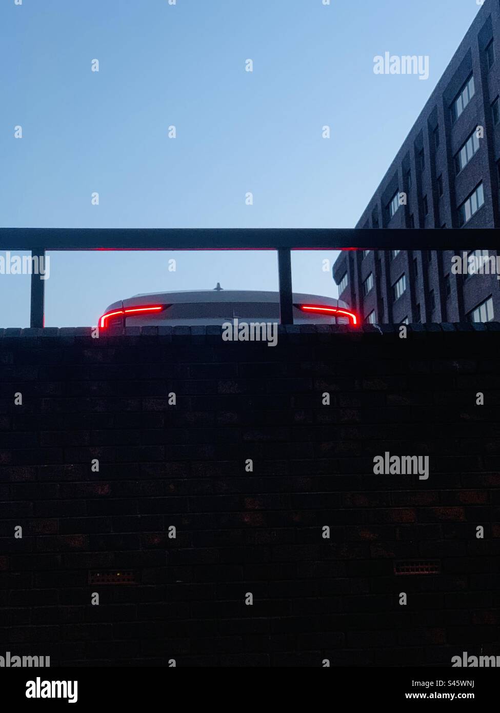 Bremslichter an einem Elektroauto auf einem städtischen Parkplatz in der Dämmerung - je Auto beleuchtet städtischen Parkplatz Kopierraum Stockfoto