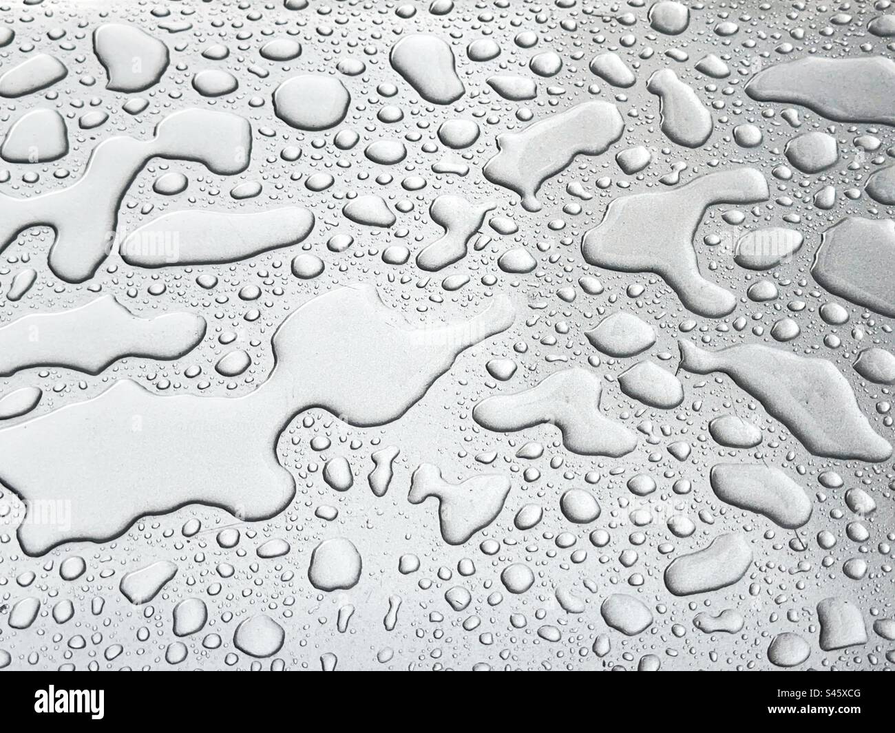 Muster, das durch Wassertropfen auf einer glänzenden Metalloberfläche gebildet wird. Hintergründe. Stockfoto
