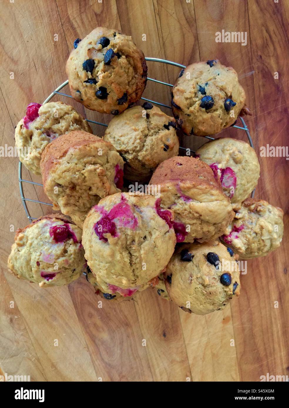 Sehr frische Muffins auf einem Kühldrahtgestell. Schneidebrett. Holzmaserung. Natürlich. Stockfoto