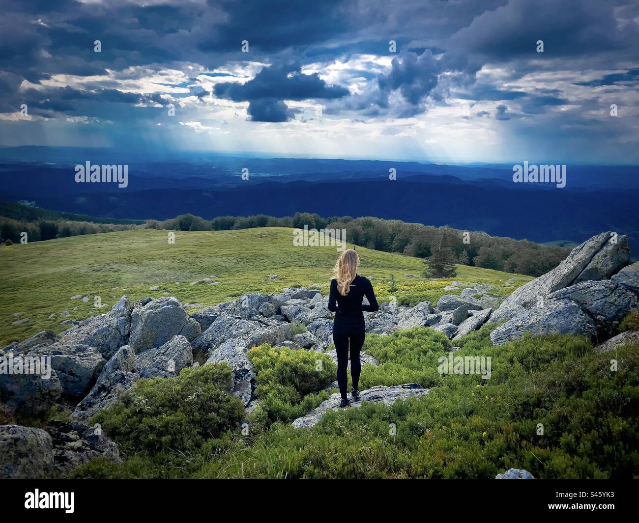Rückansicht einer fitten Wanderin mit Blick auf die Berge an einem kalten und bewölkten Sommertag Stockfoto