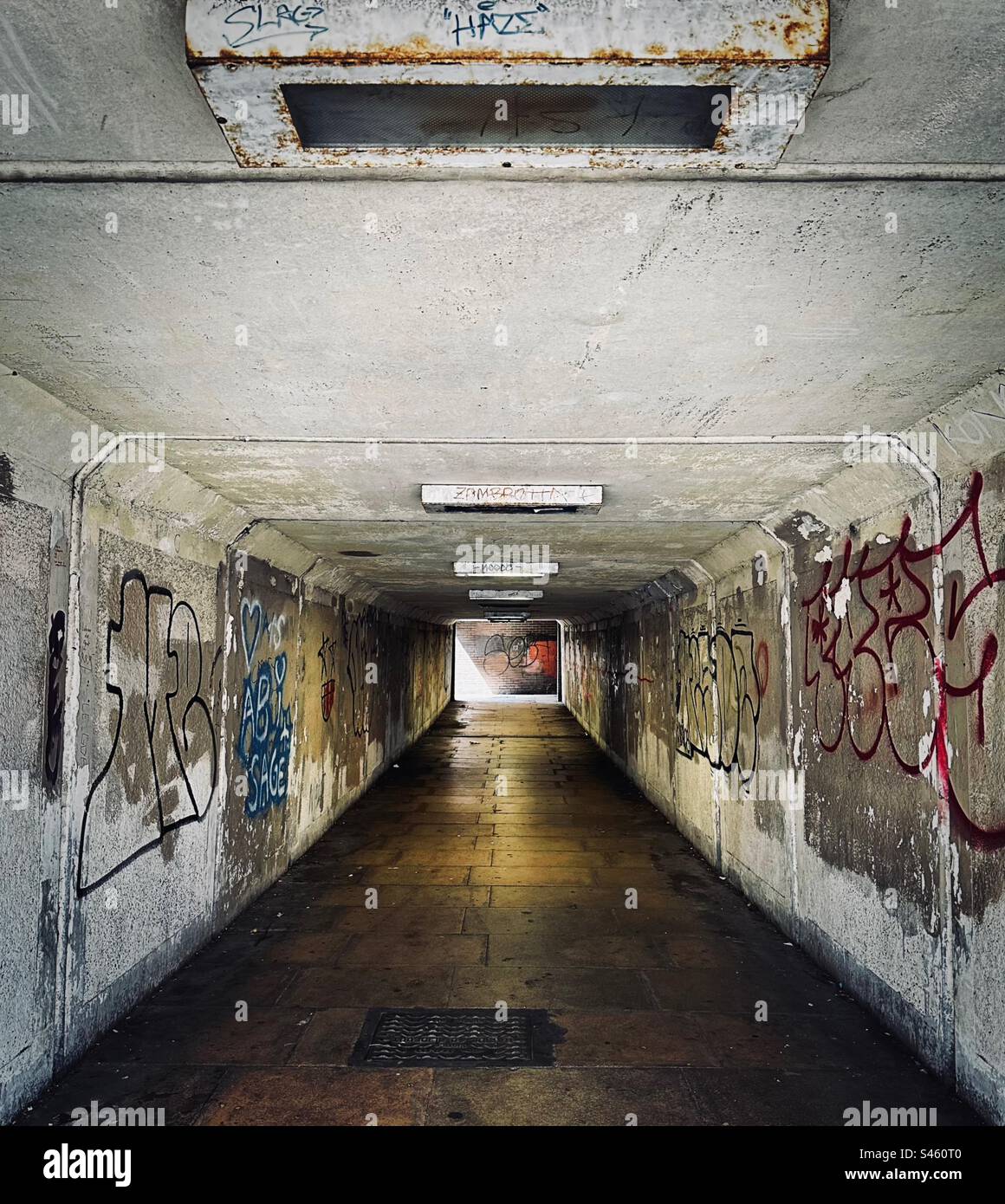 Eine U-Bahn sieht nicht einladend aus - dunkel, feucht und heruntergekommen. Graffiti-besprühte Wände befinden sich auf beiden Seiten des Gangs. Stockfoto