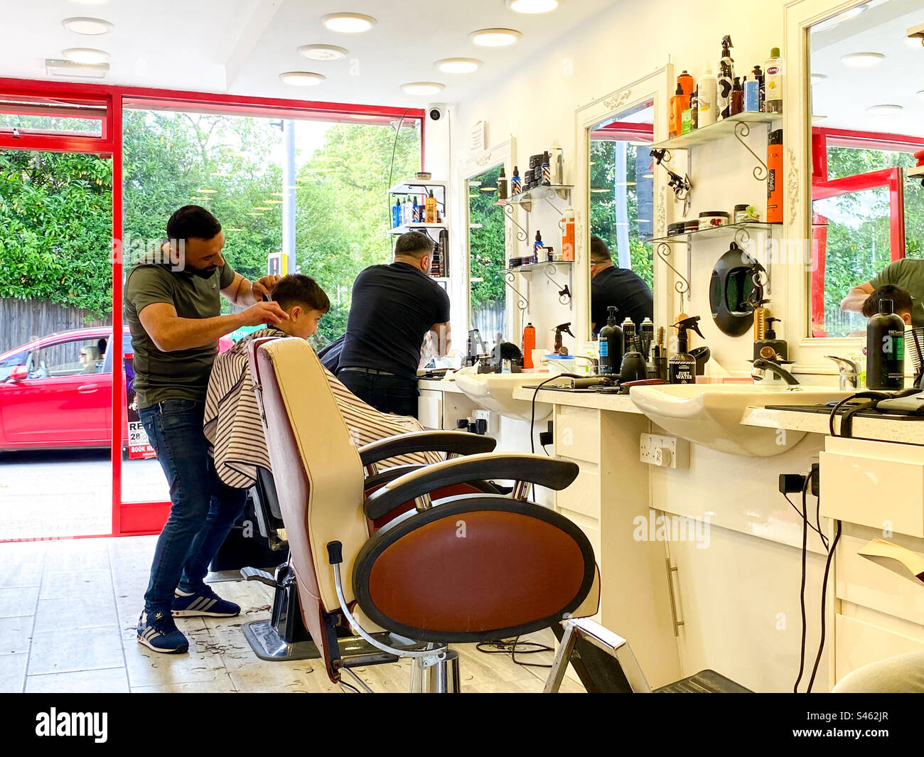Friseure bei der Arbeit in einem Friseursalon, die den Kunden die Haare schneiden. - Smartphone-aufgenommenes Stockfoto